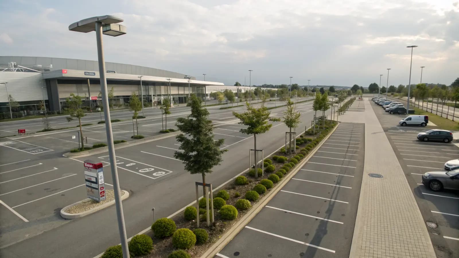 Weitläufiger Parkplatz eines Einkaufszentrums mit begrünten Inseln (illustrative Szene)